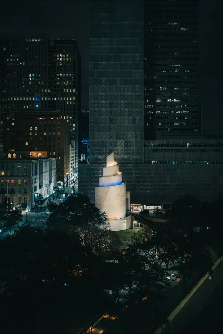 High-angle night view of the Chapel of Thanksgiving in Dallas, showing its spiral shell architecture illuminated.