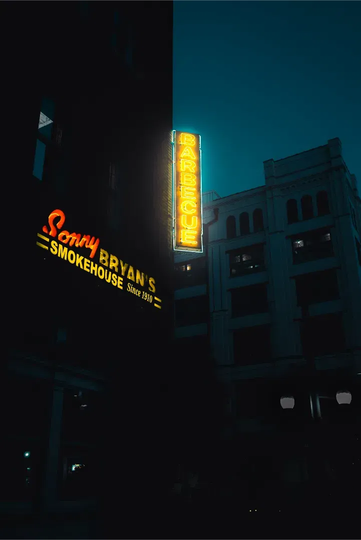 Moody night shot of the glowing neon sign for Sonny Bryan's Smokehouse BBQ joint.
