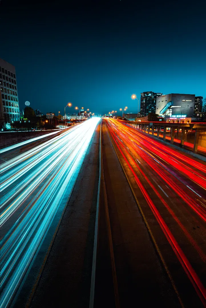 Long exposure highway traffic trails split into cyan/white headlights on the left and red taillights on the right.