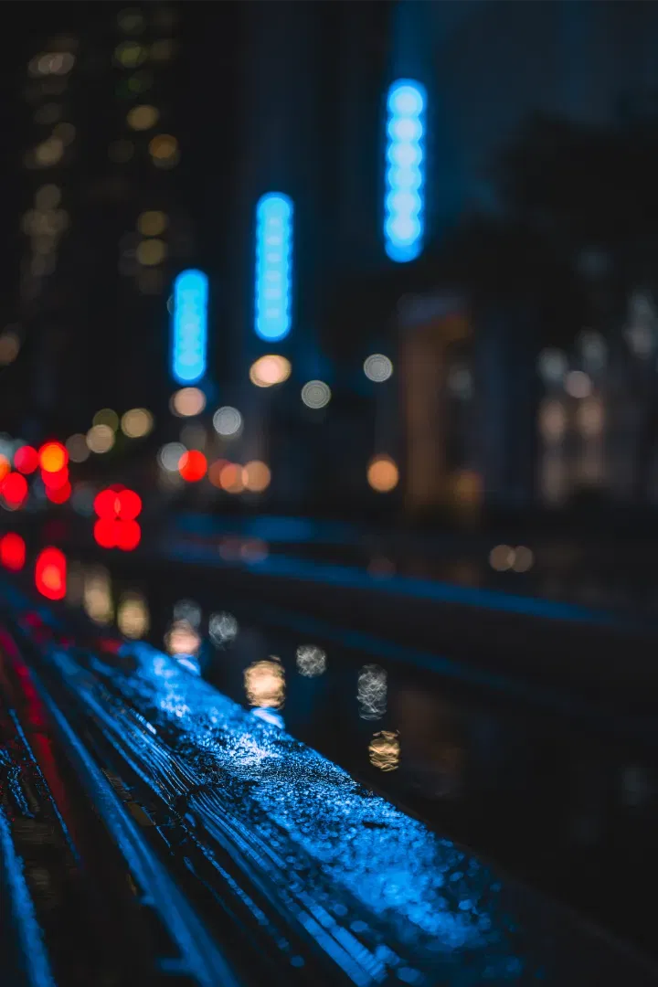 Close-up, shallow depth of field shot of wet textures at night, with beautiful blue and red bokeh lights.