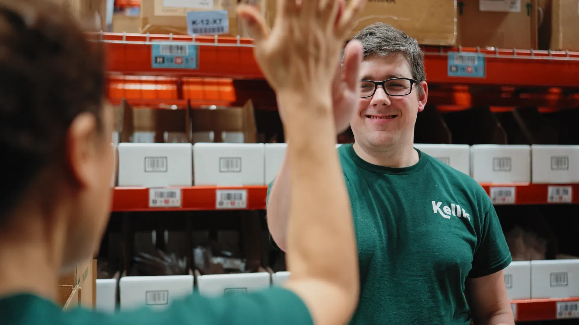 Kelli's warehouse team members celebrating with a high five in the distribution center