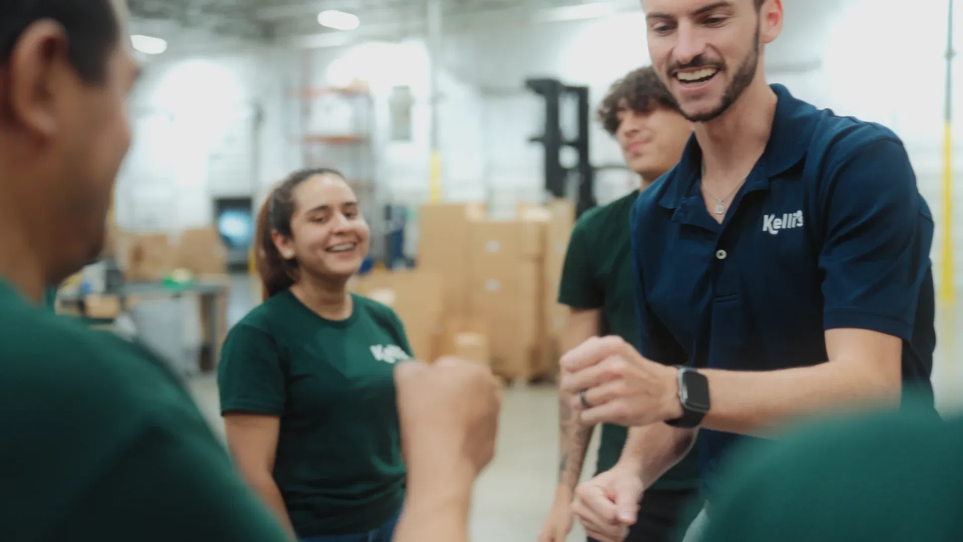 Operations leads and warehouse crew sharing a team huddle fist bump in the facility